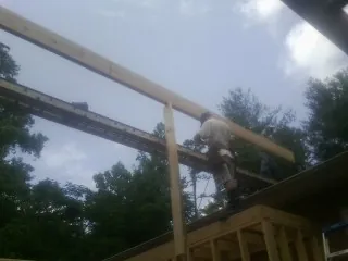 Carpenter setting a ridge beam over a new addition frame — Ice Dam Removal by Roofing Brothers in National City
