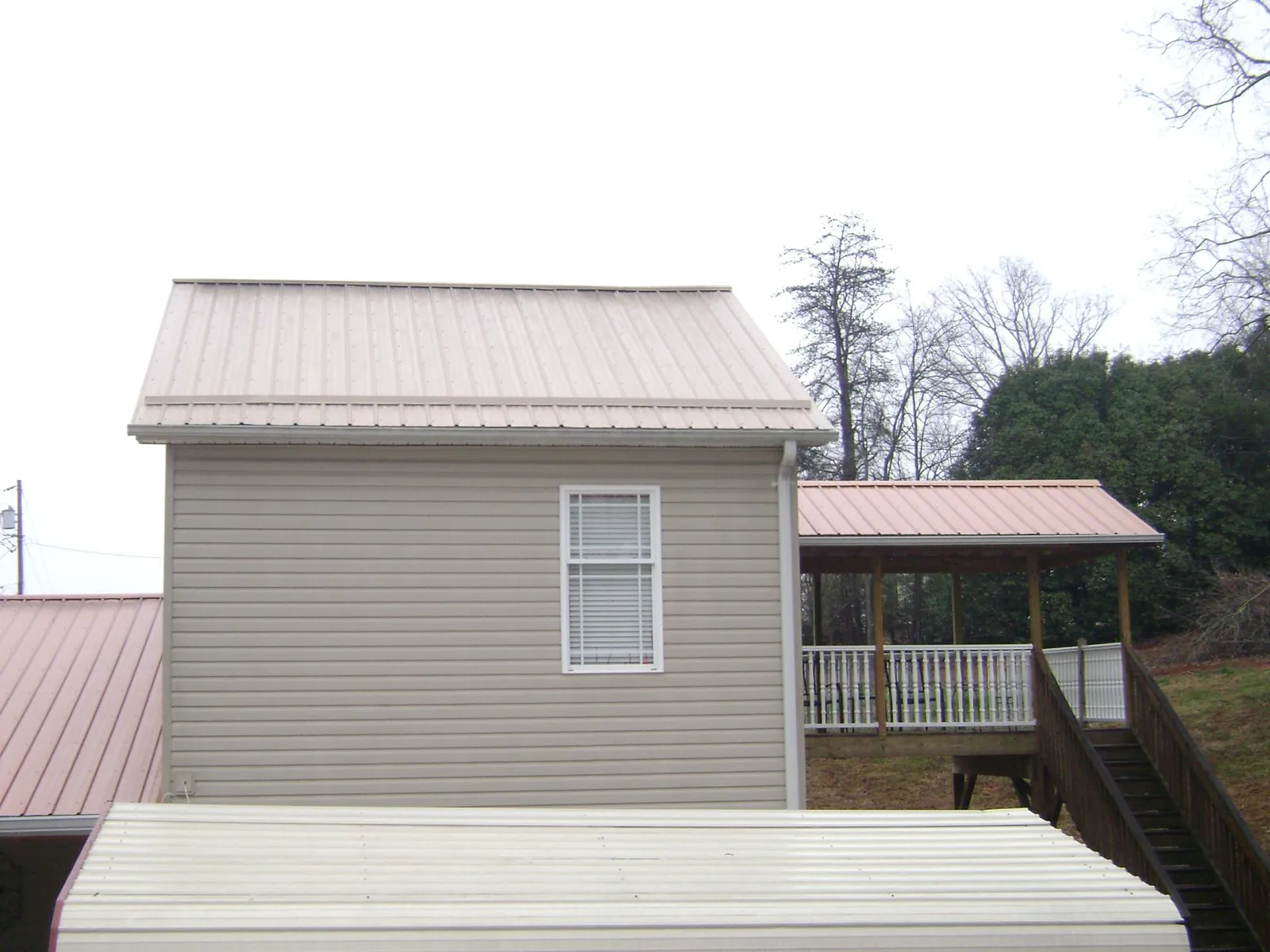 Tan metal roofs on a two story addition and attached porch, from a Roof Replacement job in National City