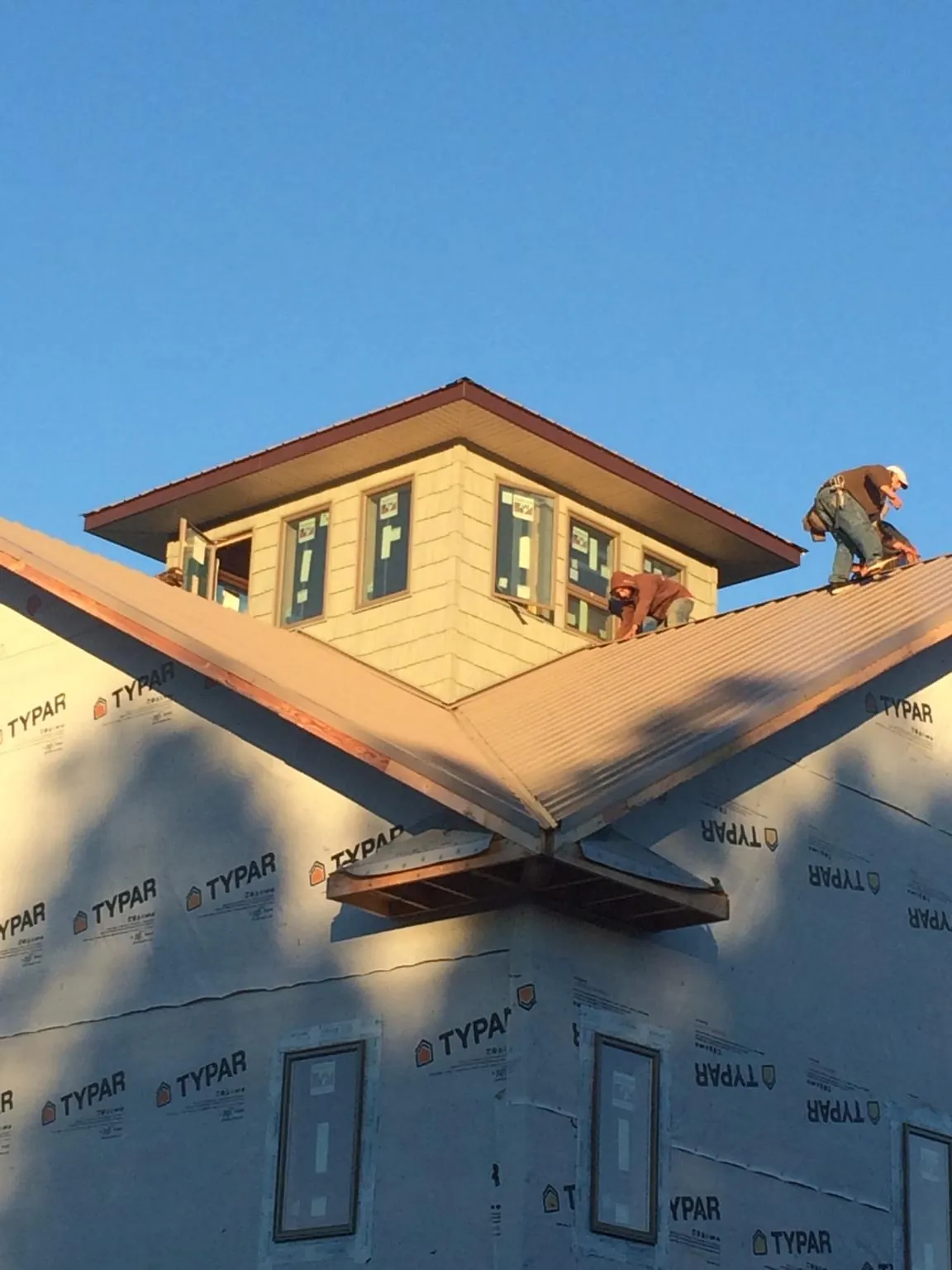 Roofers working around a rooftop cupola on a new metal roof at sunset — Roof Waterproofing in National City by Roofing Brothers